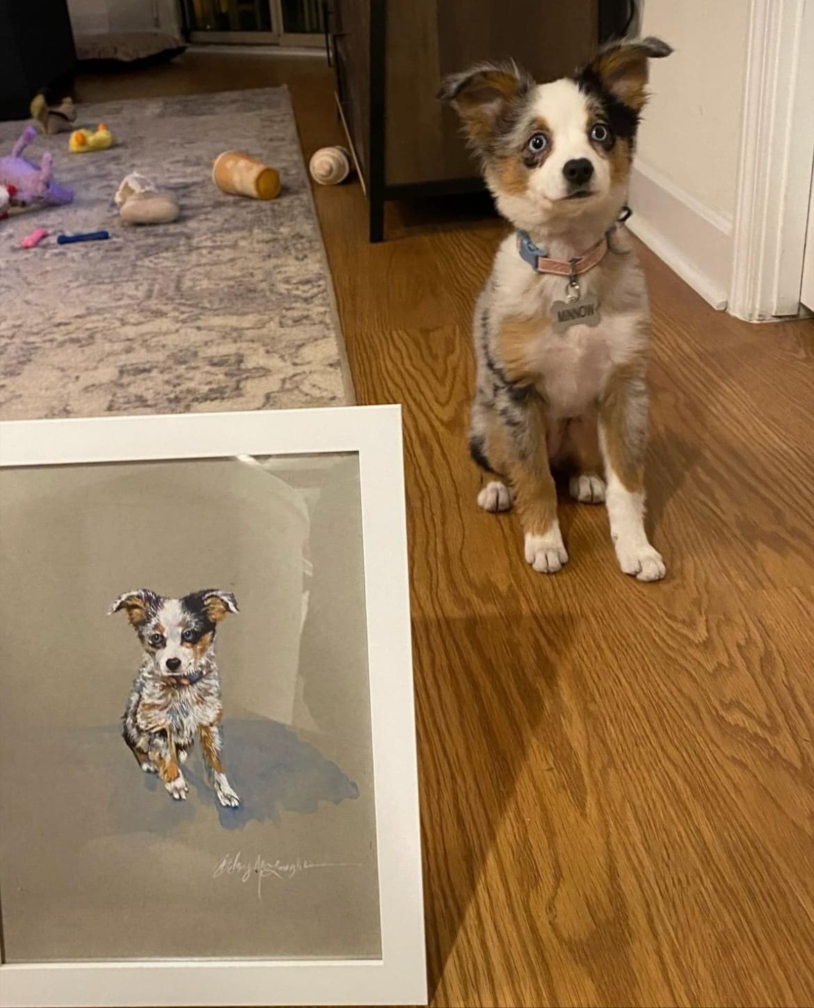 A dog is standing next to a painting of itself.