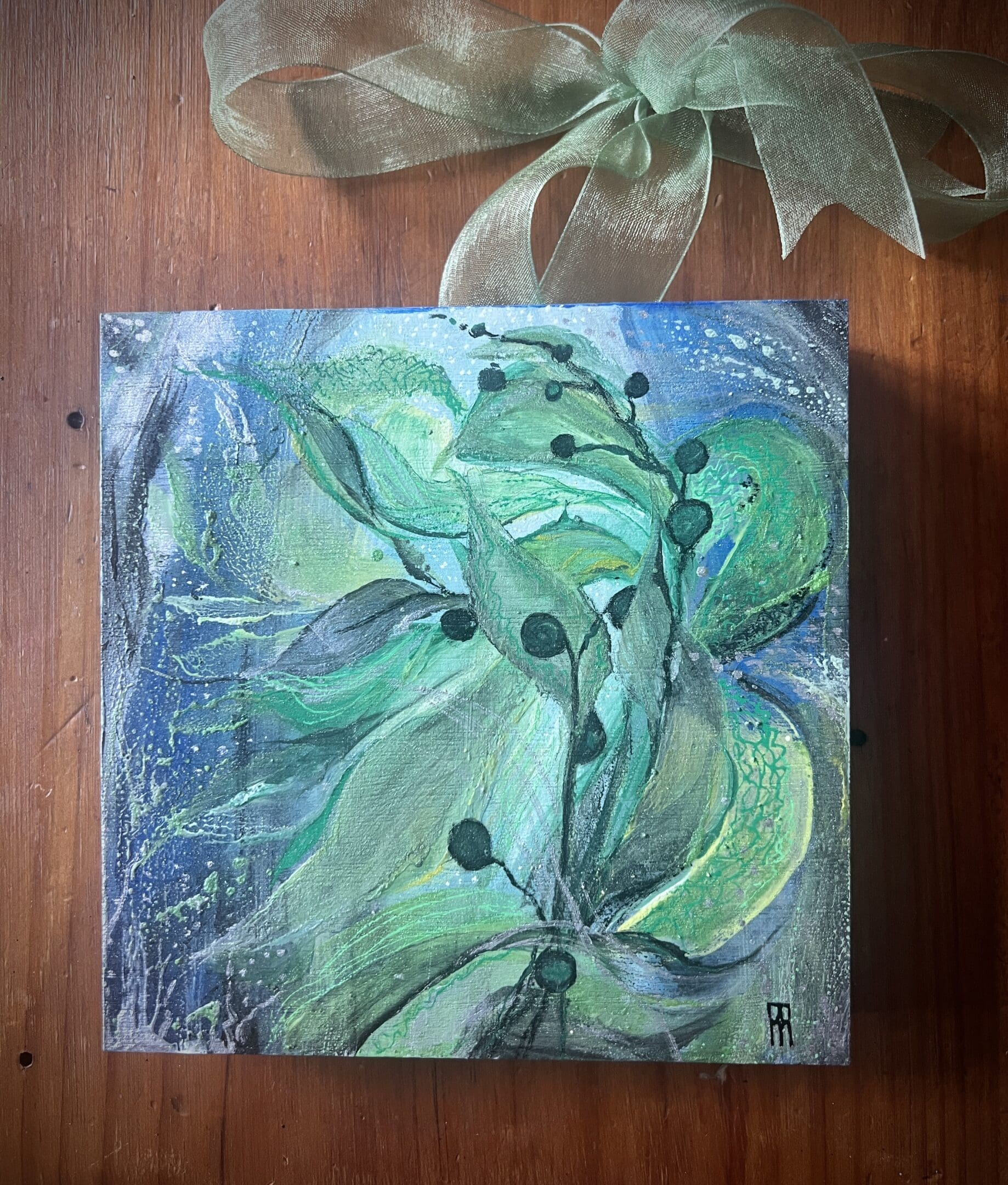 A painting of green leaves on top of a wooden table.